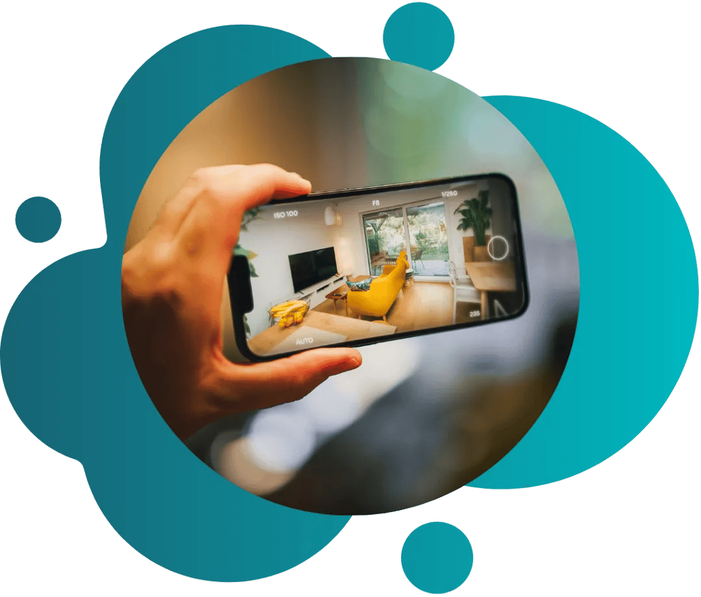 Hand mit Smartphonekamera und vollmöbliertem Wohnzimmer darauf