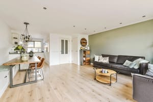 a living room with wood flooring and green walls, including a black sofa in the center of the room