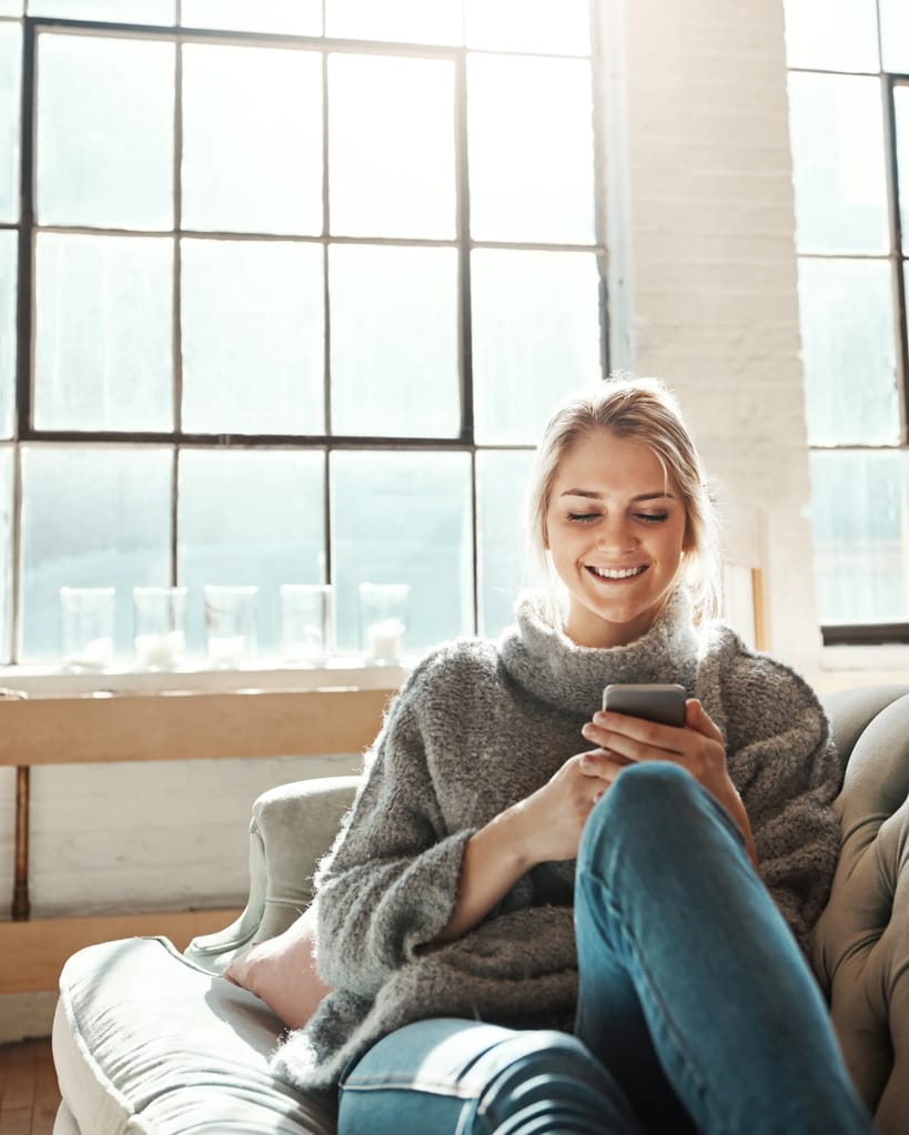 Woman looking on smartphone sitting on a couch