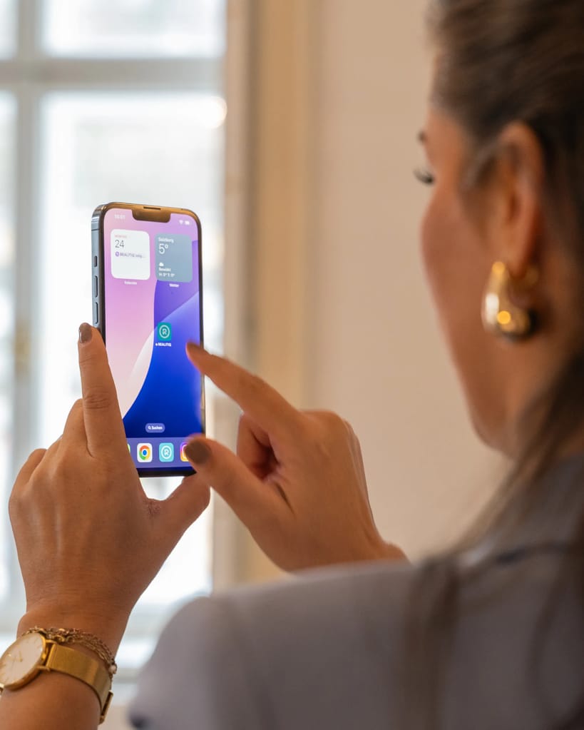 Person mit Smartphone tippt auf REALITIQ-App