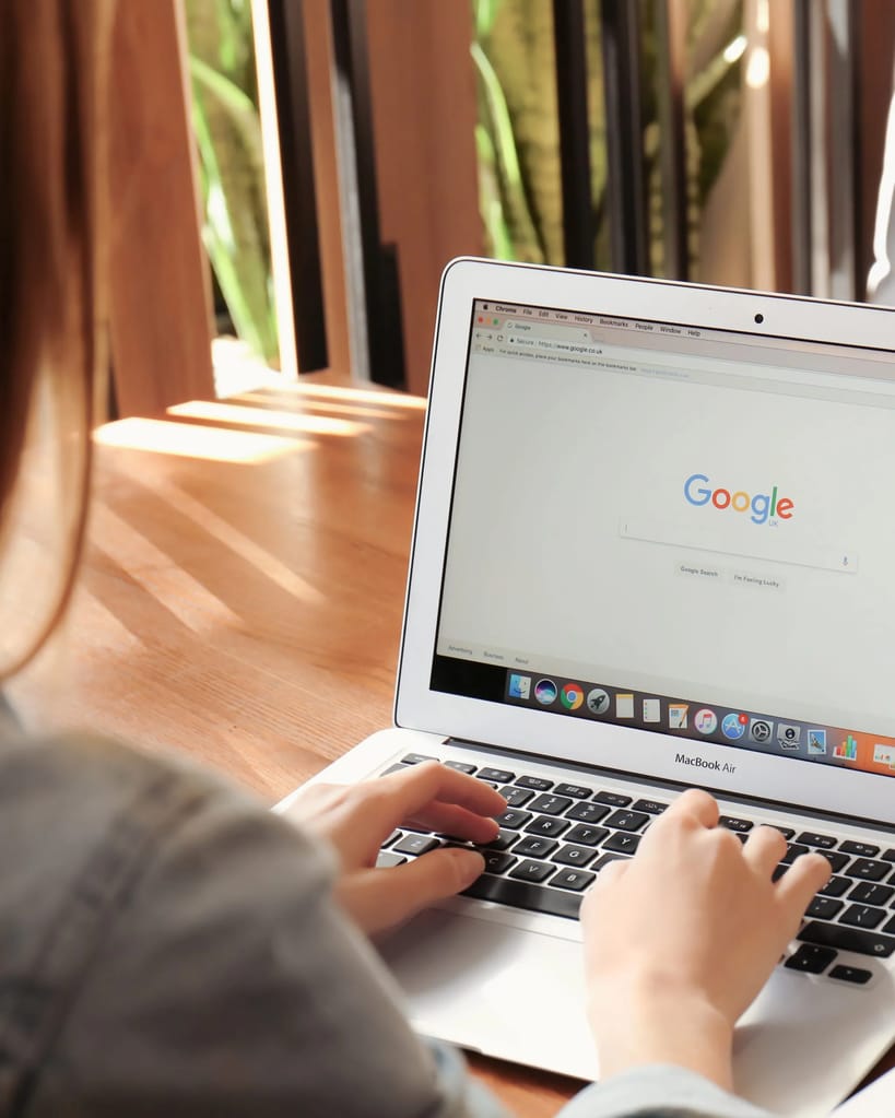 Young woman using Apple Macbook Air with Google search page on screen in cafe